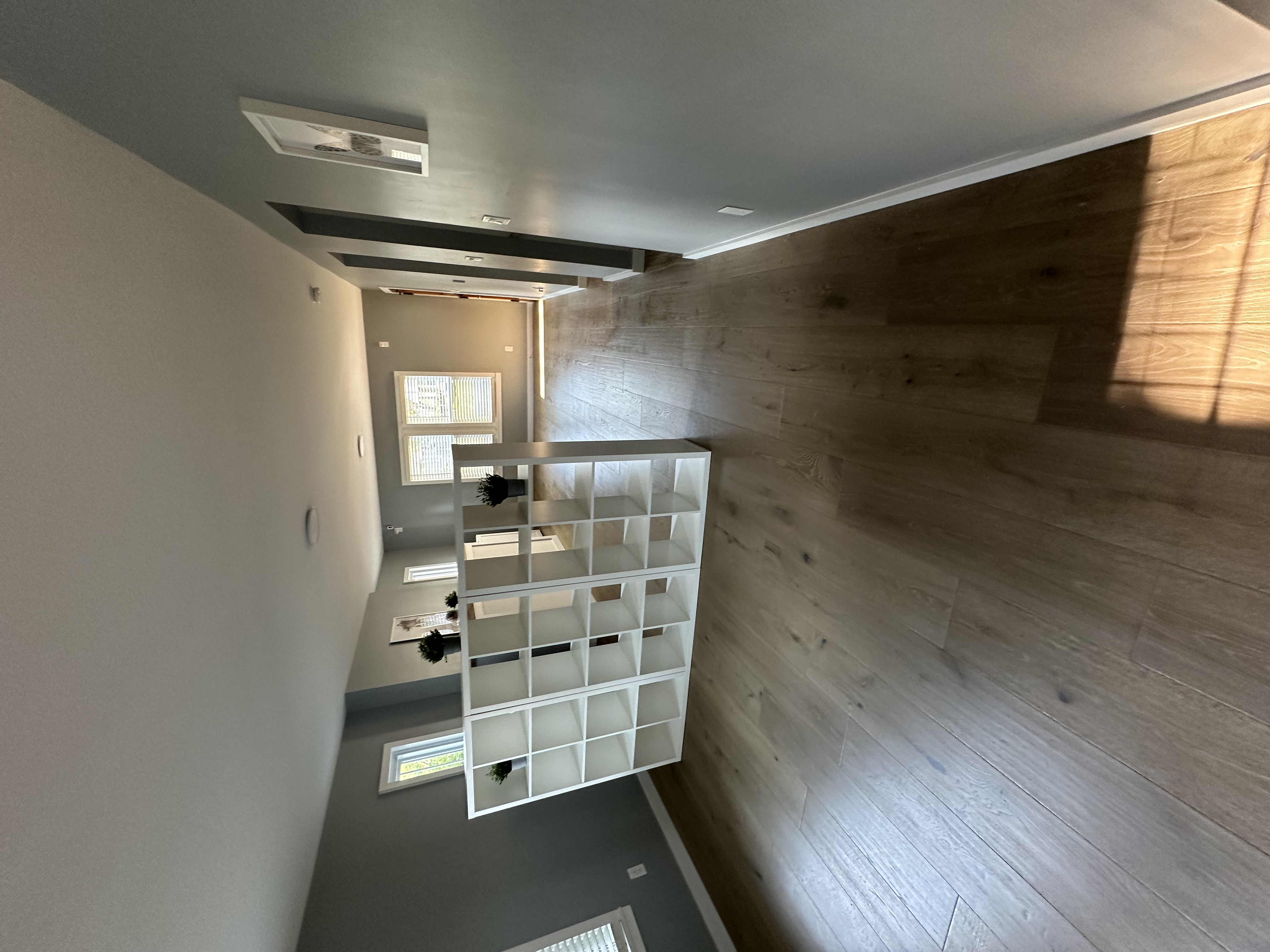 View through bookshelf divider toward kitchen and hallway